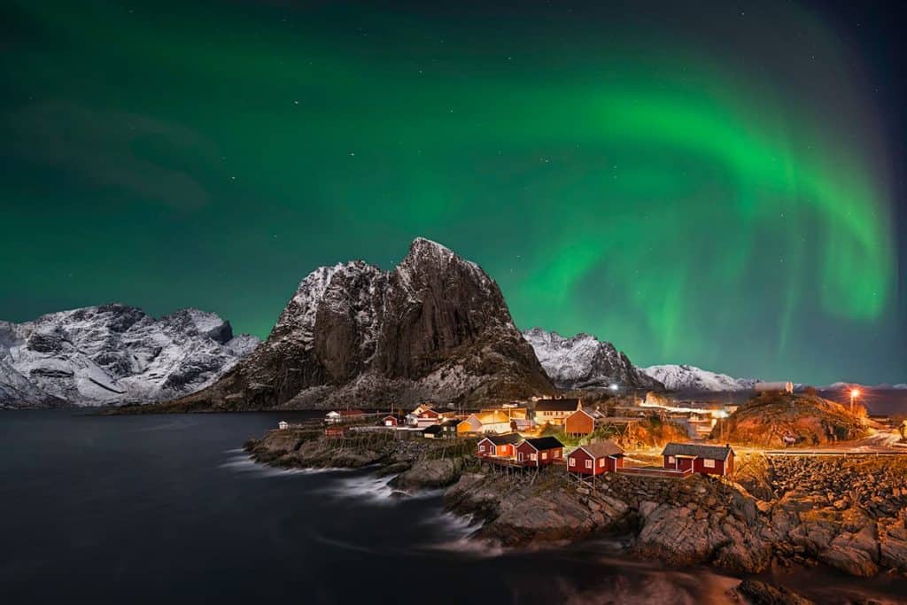 Noorderlicht met verlichte huizen in de Lofoten in Noorwegen